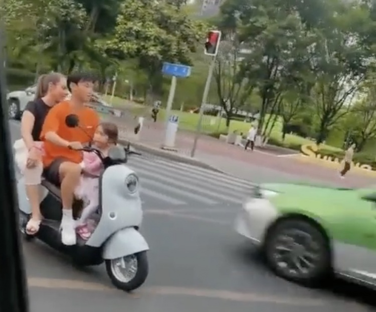 杨明洋在成都街头骑电动车载妻女未